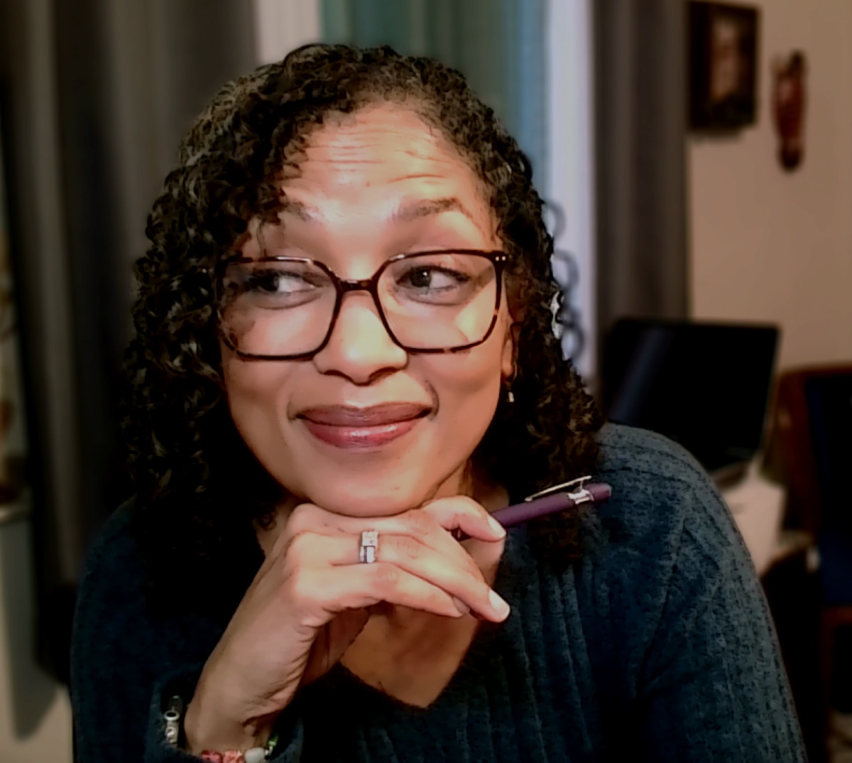 Naomi V. Dunsen-White wearing glasses and holding a pen while looking to the side