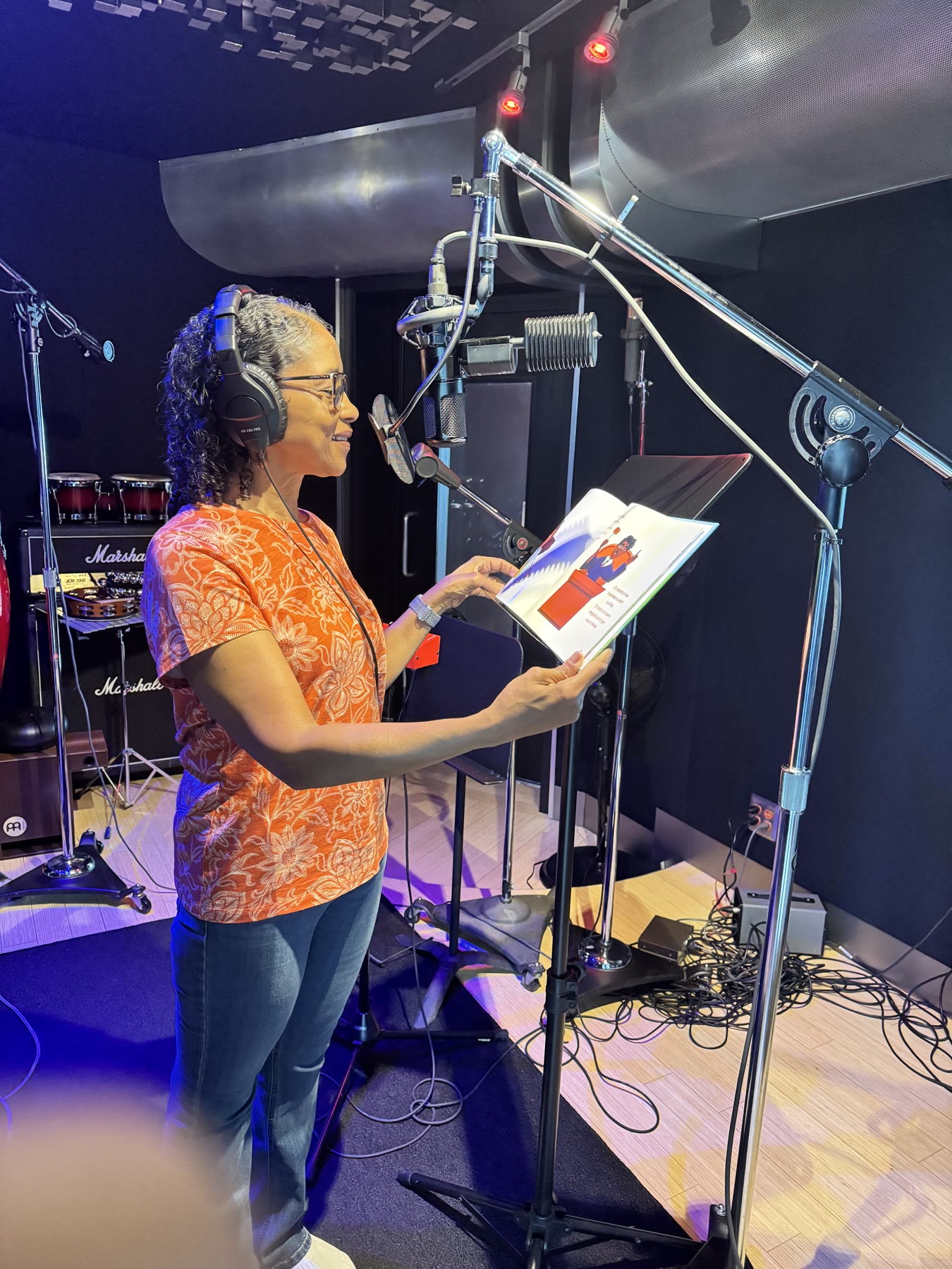 Naomi wearing studio headphones and reading the bilingual edition into a microphone