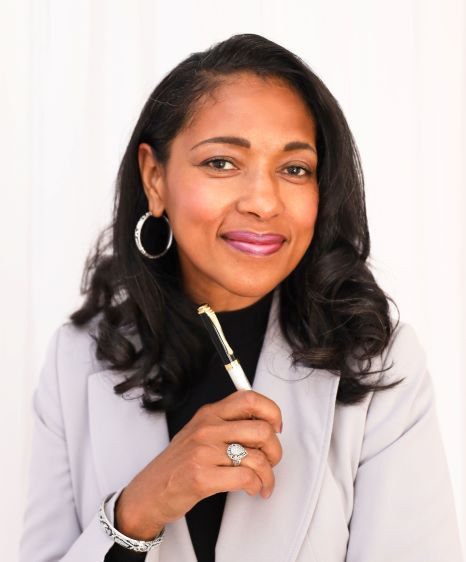 Naomi V. Dunsen-White smiling with a pen in hand