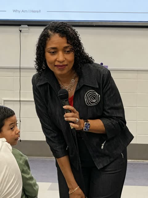 Naomi V. Dunsen-White speaking with a microphone during a school visit