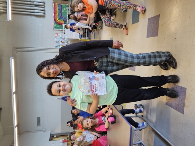 Naomi V. Dunsen-White standing with a smiling young reader holding Johari the Great