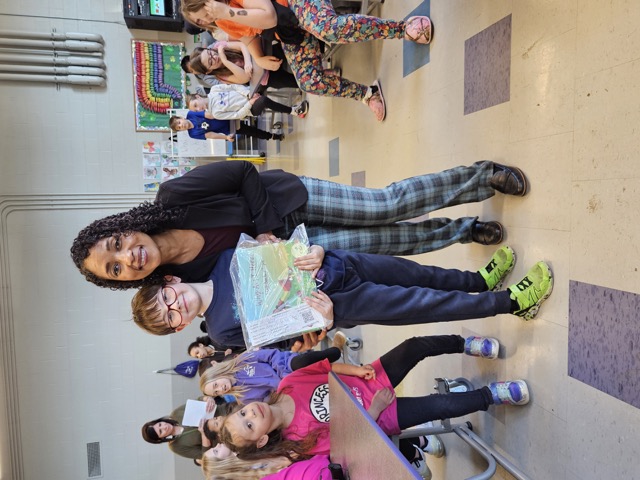 Naomi V. Dunsen-White standing with a young reader proudly holding a book