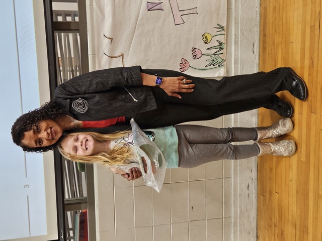 Naomi V. Dunsen-White smiling with a young reader after a school presentation
