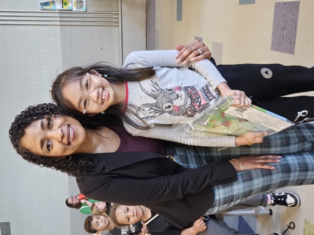 Naomi V. Dunsen-White smiling beside a young reader holding a book