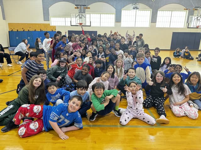Naomi V. Dunsen-White surrounded by smiling students during a Novi Woods school visit
