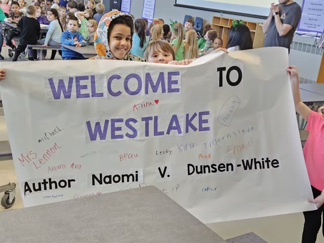 Students holding a handmade welcome banner for Naomi V. Dunsen-White